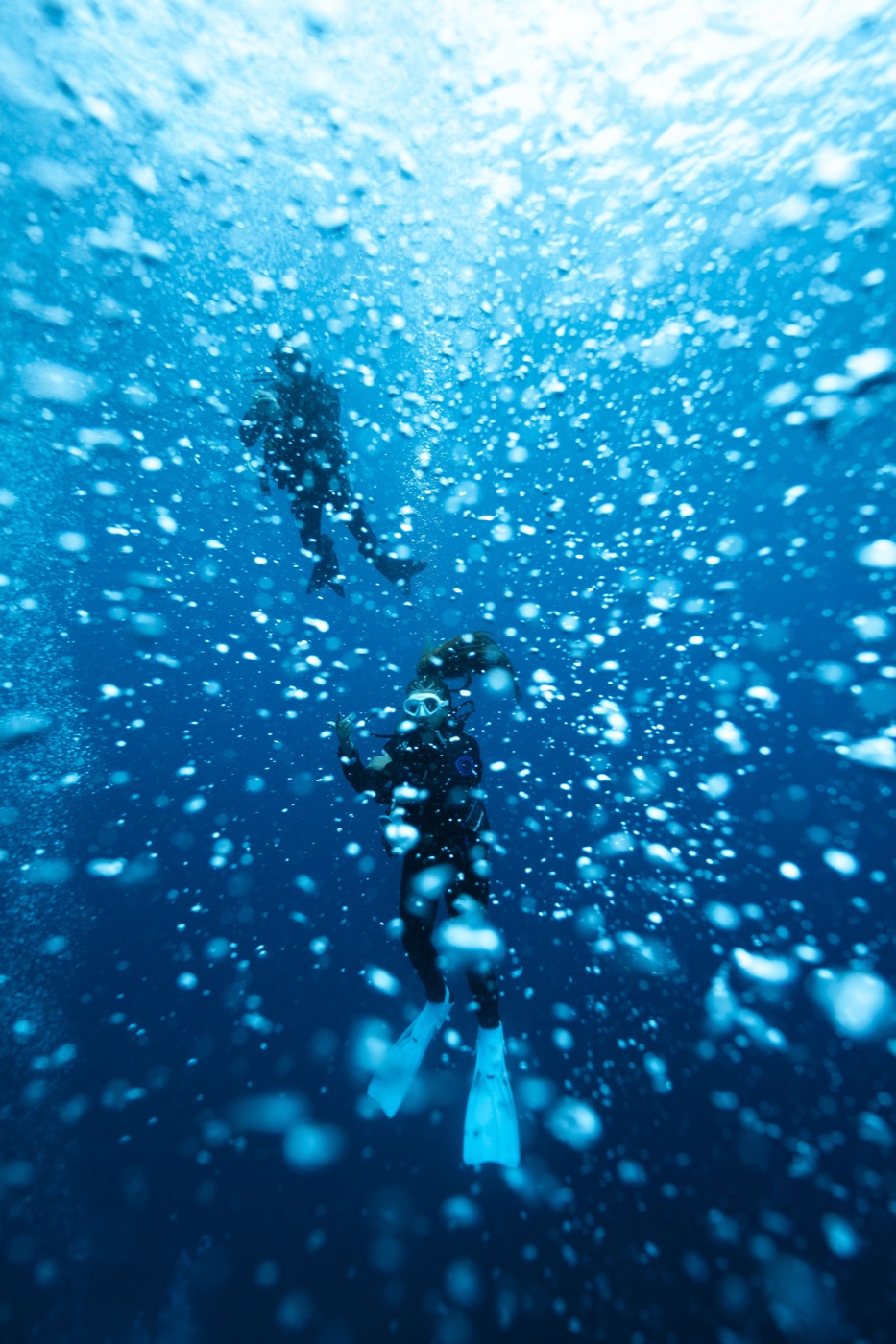 Divers ascending through bubbles